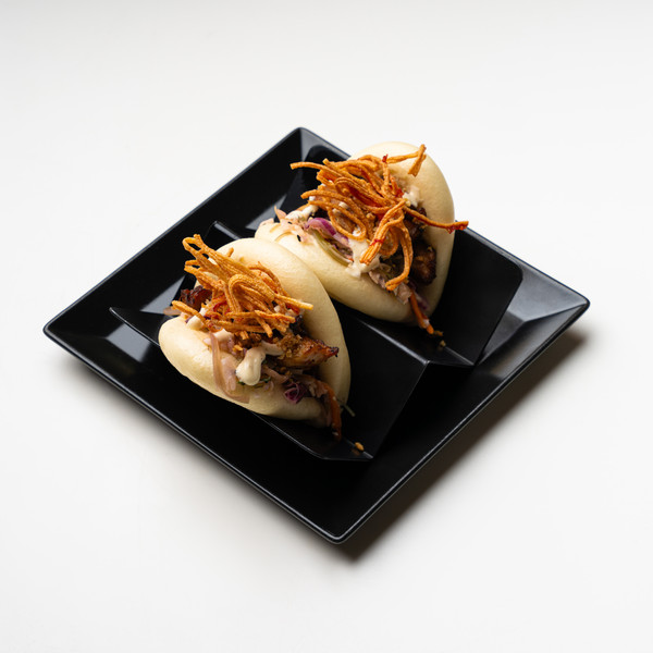 Bao buns με γέμιση, sauce και crispy noodles σε μαύρο πιάτο.