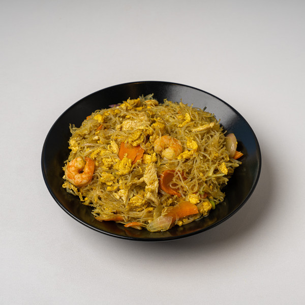 Rice noodles με γαρίδες, κοτόπουλο, αυγό και λαχανικά σε μαύρο μπολ.