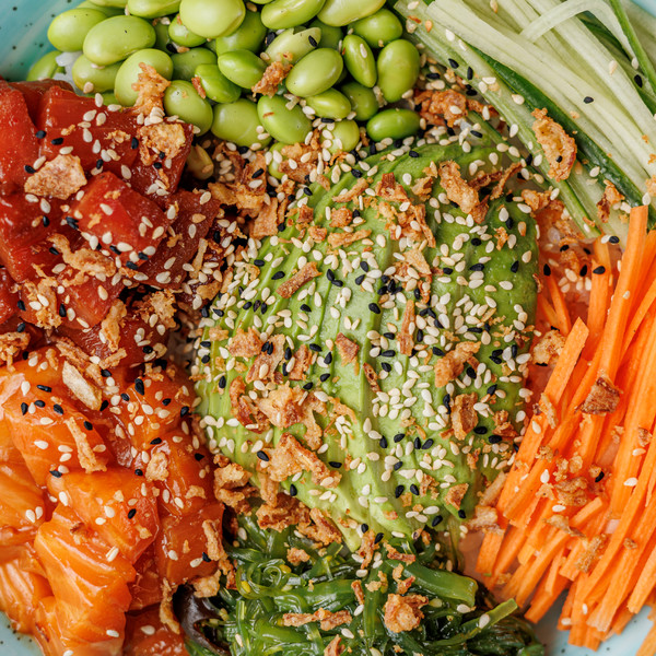 Πολύχρωμο poke bowl με σολομό, αβοκάντο, edamame, καρότο και σουσάμι.